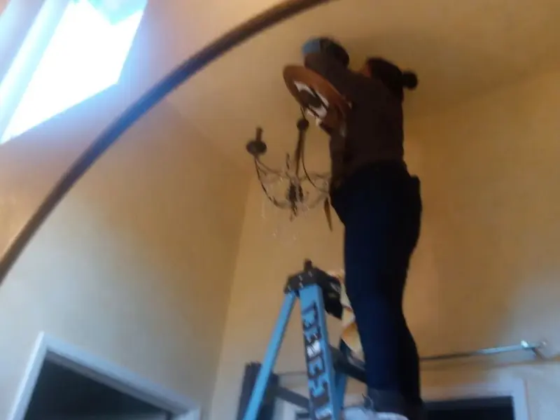 Electrician installing a chandelier in a Boonville residence